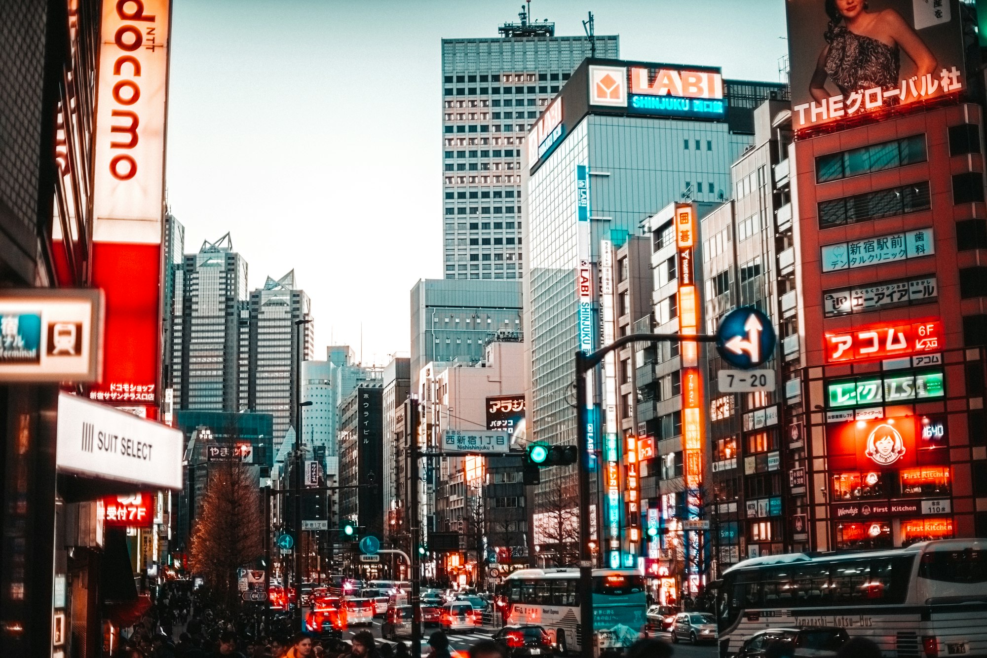 낮의 신주쿠, 고층 건물과 간판 사이로 차들이 지나는 큰길